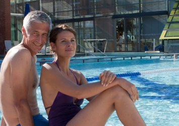 Ein Paar mittleren Alters sitzt entspannt draußen am Schwimmbecken