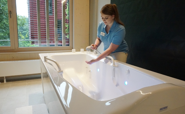Eine Angestellte prüft die Wassertemperatur mit der Hand beim Wassereinlauf in einer modernen Badewanne