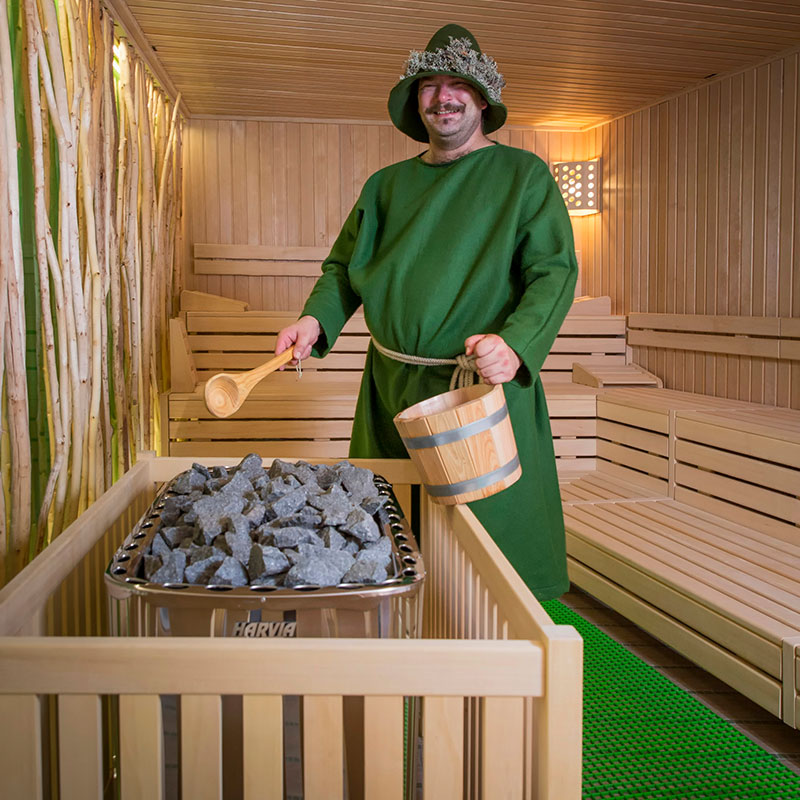 Moosmann Sauna Innenansicht mit einem Mann, der Saunaaufguss macht