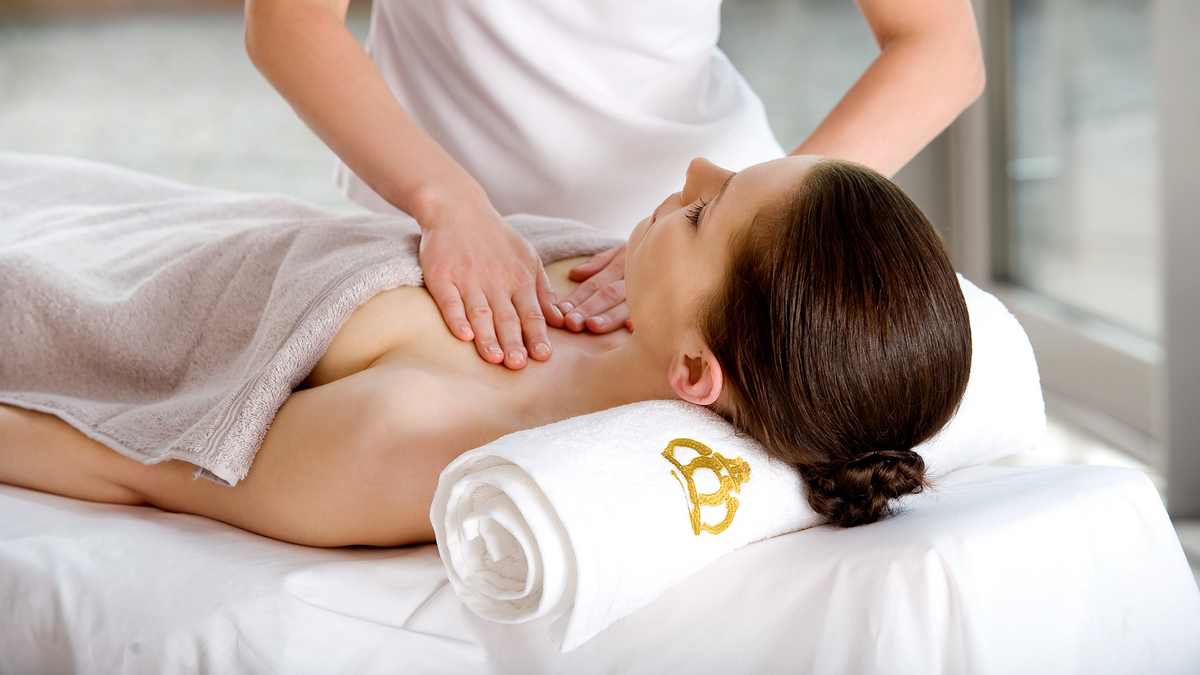 Eine Frau liegt mit dem Rücken auf einer Massageliege und bekommt eine Dekolleté Massage