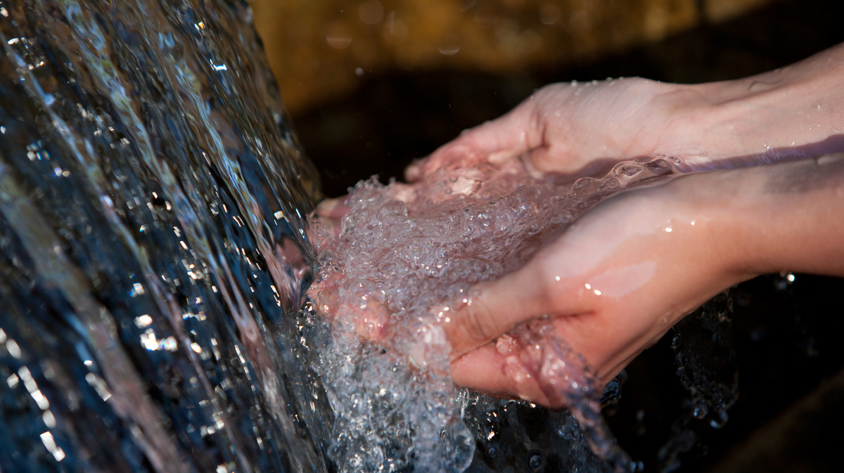 Hände fangen Wasser in aus herabfließendem Wasser auf
