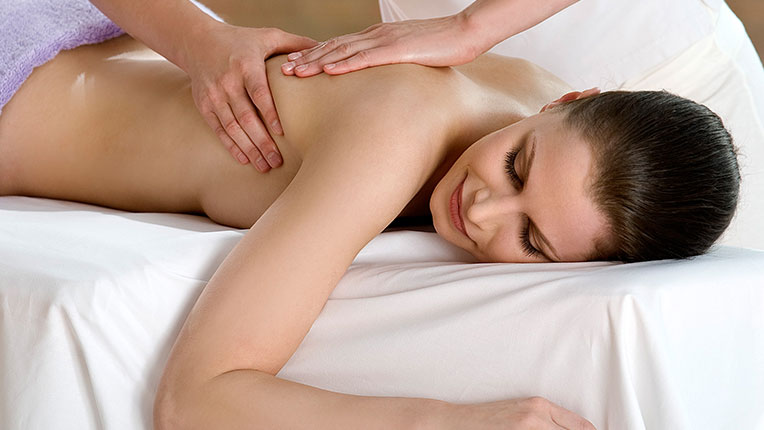 Eine Frau liegt auf einer Physiotherapie-Liege und wird massiert