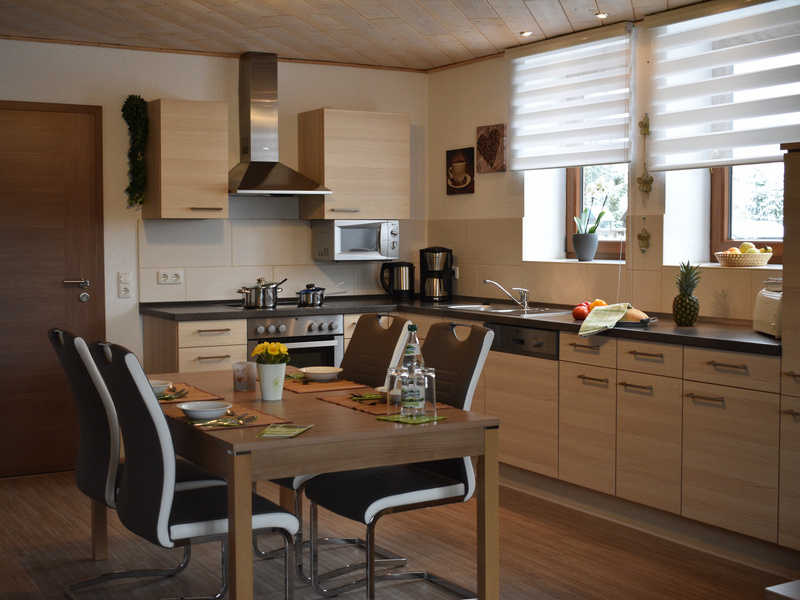 Voll ausgestattete Einbauküche mit Esstisch und Stühlen