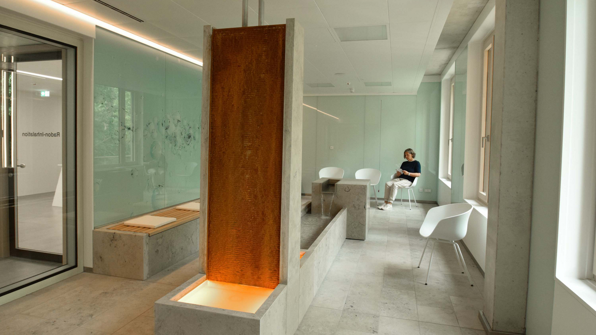 Eine Frau sitzt in einer Ecke auf einem Stuhl im Inhalationsraum des Radon-Therapiezentrums