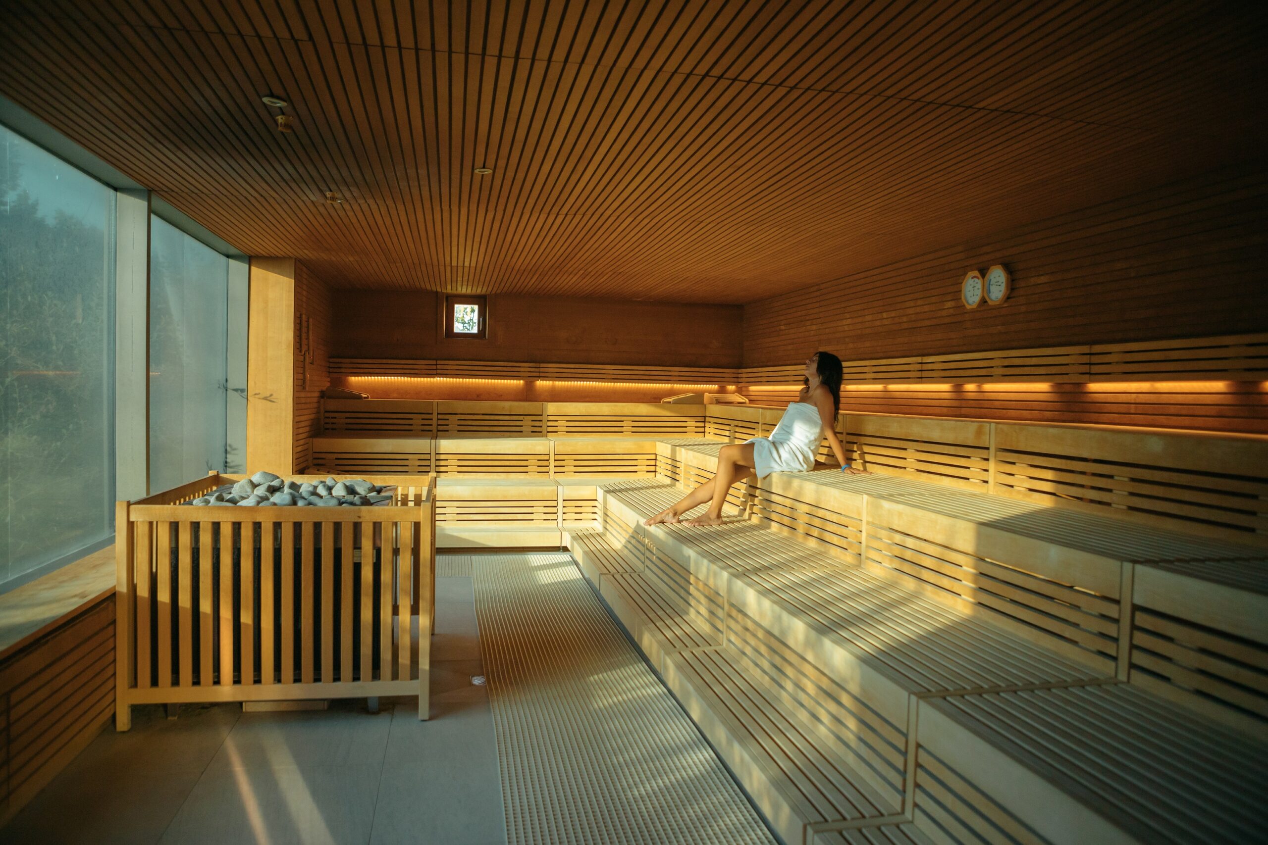 Eine Frau sitzt in der Sauna und schaut zum Fenster raus
