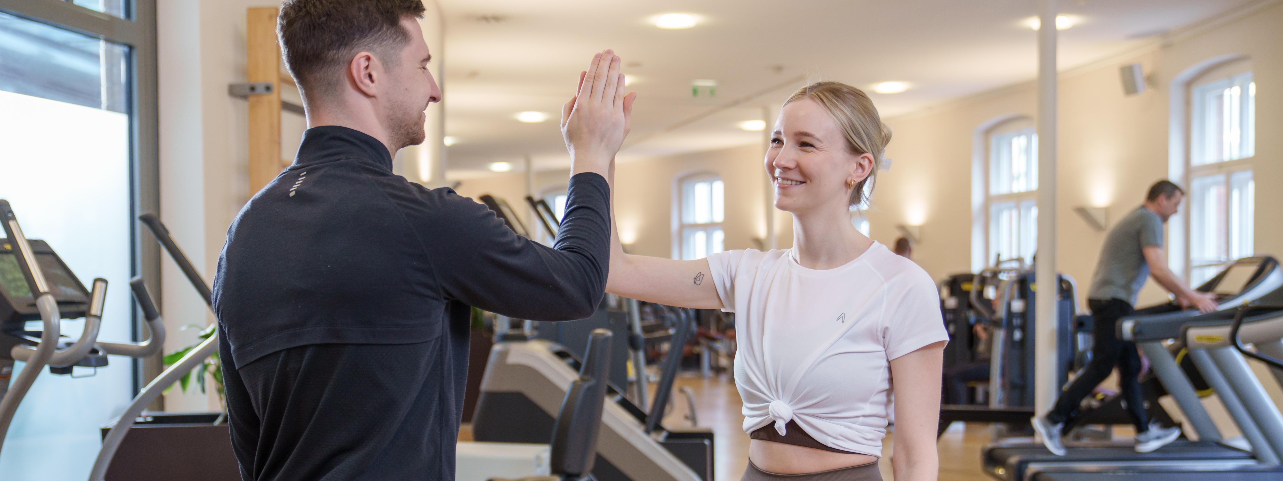 Eine Frau und ein Mann klatschen sich im Fitness-Trainingszentrum gegenseitig in die Hände