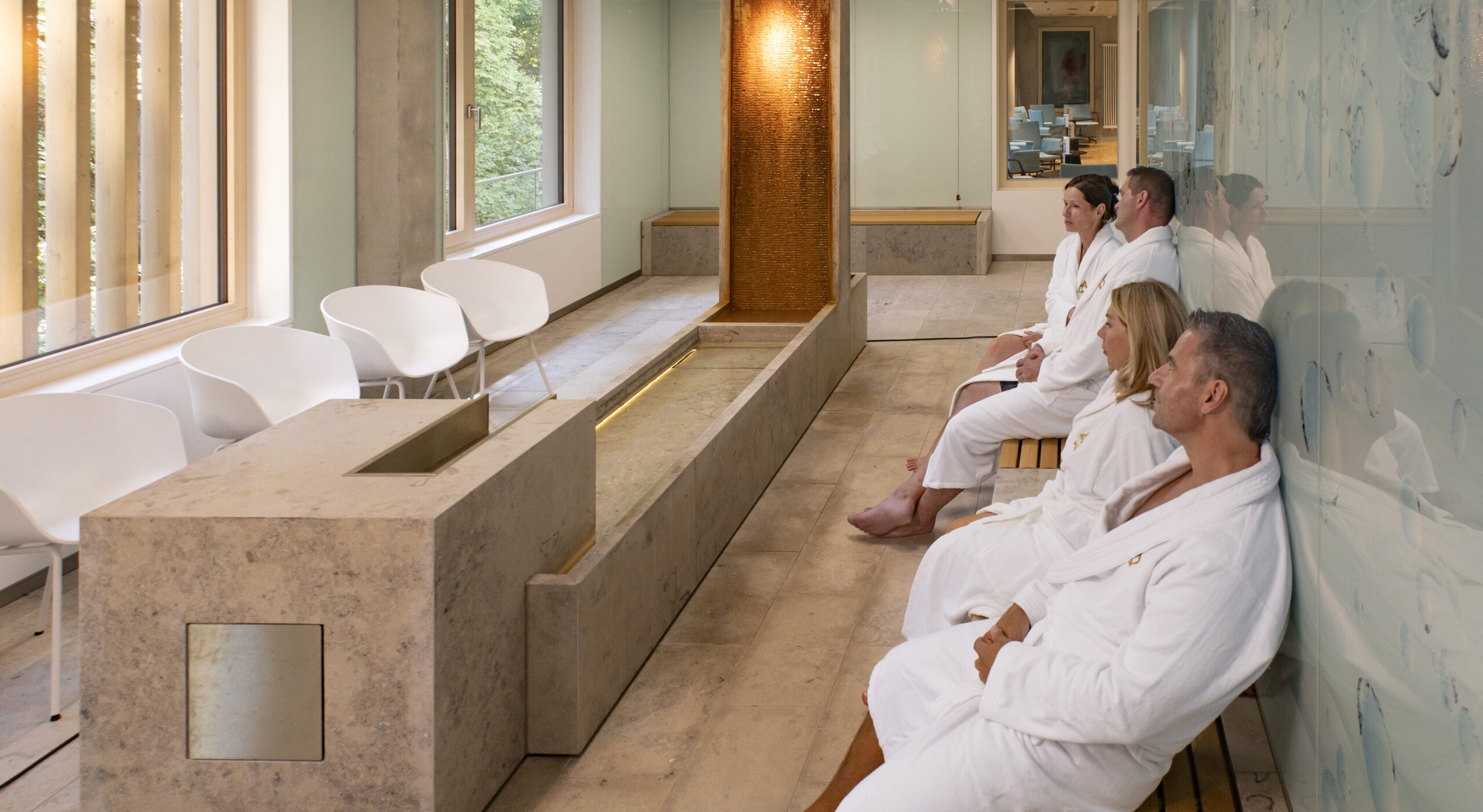 Je zwei Paare sitzen mit dem Rücken an der Wand im Radoninhalations-Raum