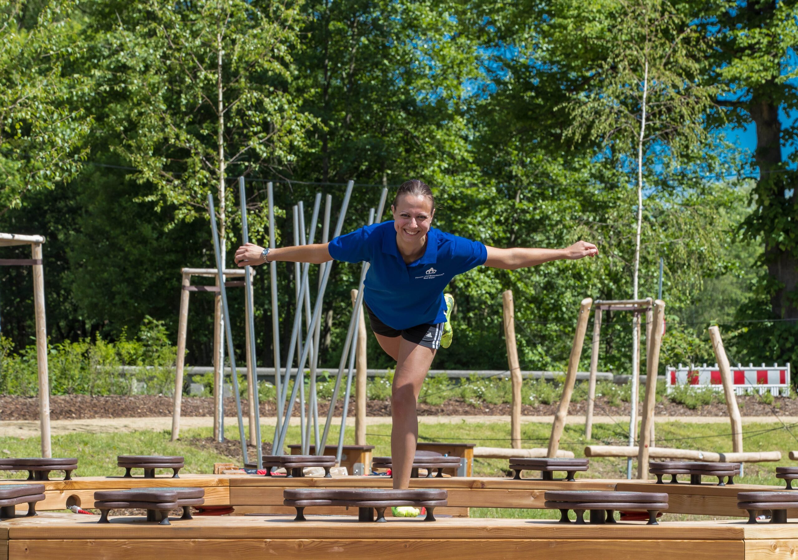 Eine Frau im Motorikpark lächelnd bei einer Gleichgewichtsübung